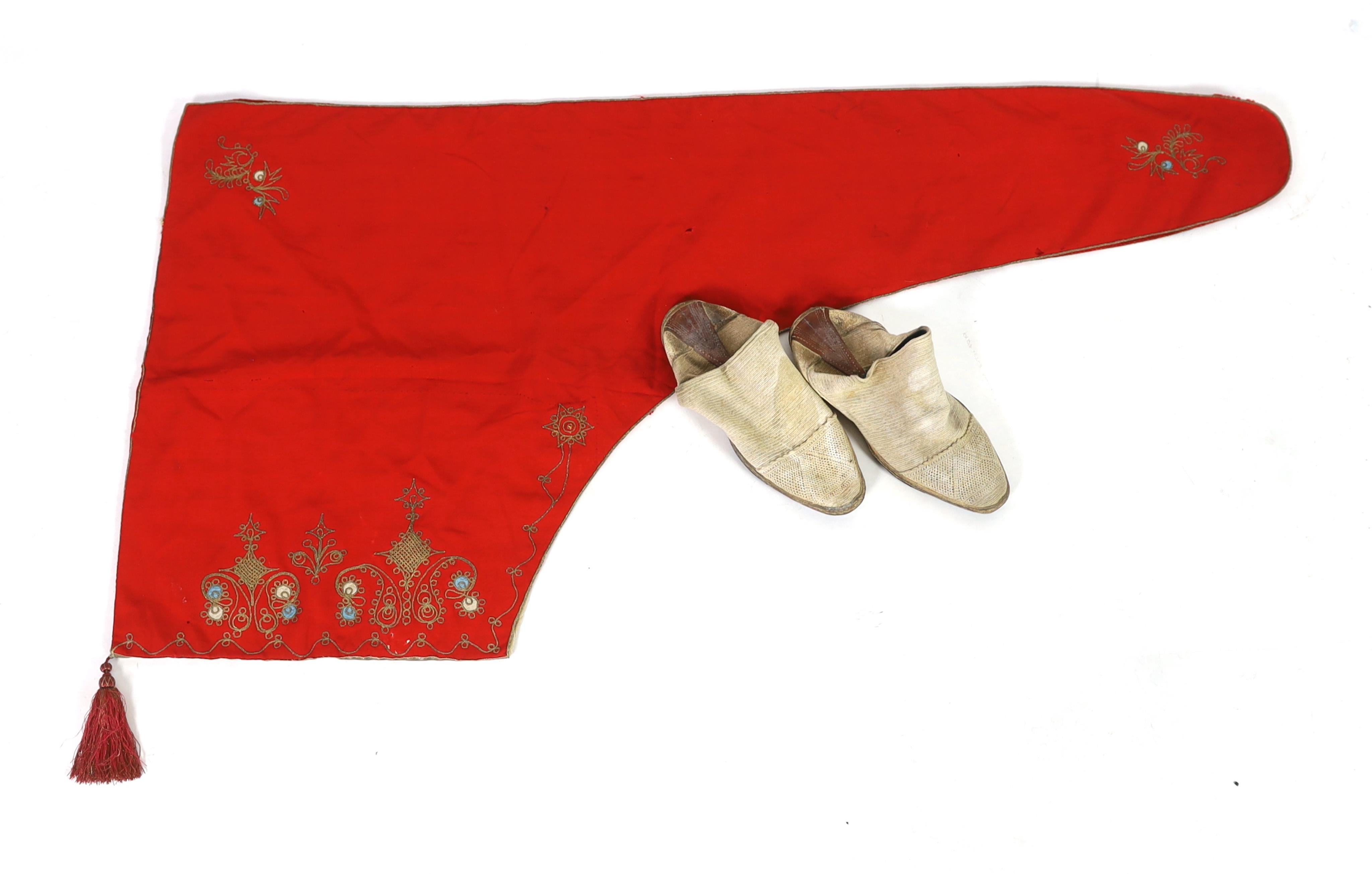 A pair of 1970's Iranian ‘Geevay’ slippers, the soles made from tyres and tops hand crochet together with a 19th century fine red wool hood with gold embroidery and a red tassel, possibly Spanish, ecclesiastical hood